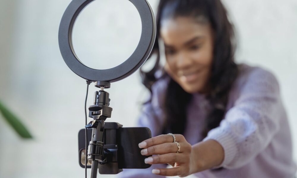 happy young black woman setting up smartphone before shooting podcast