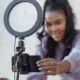 happy young black woman setting up smartphone before shooting podcast